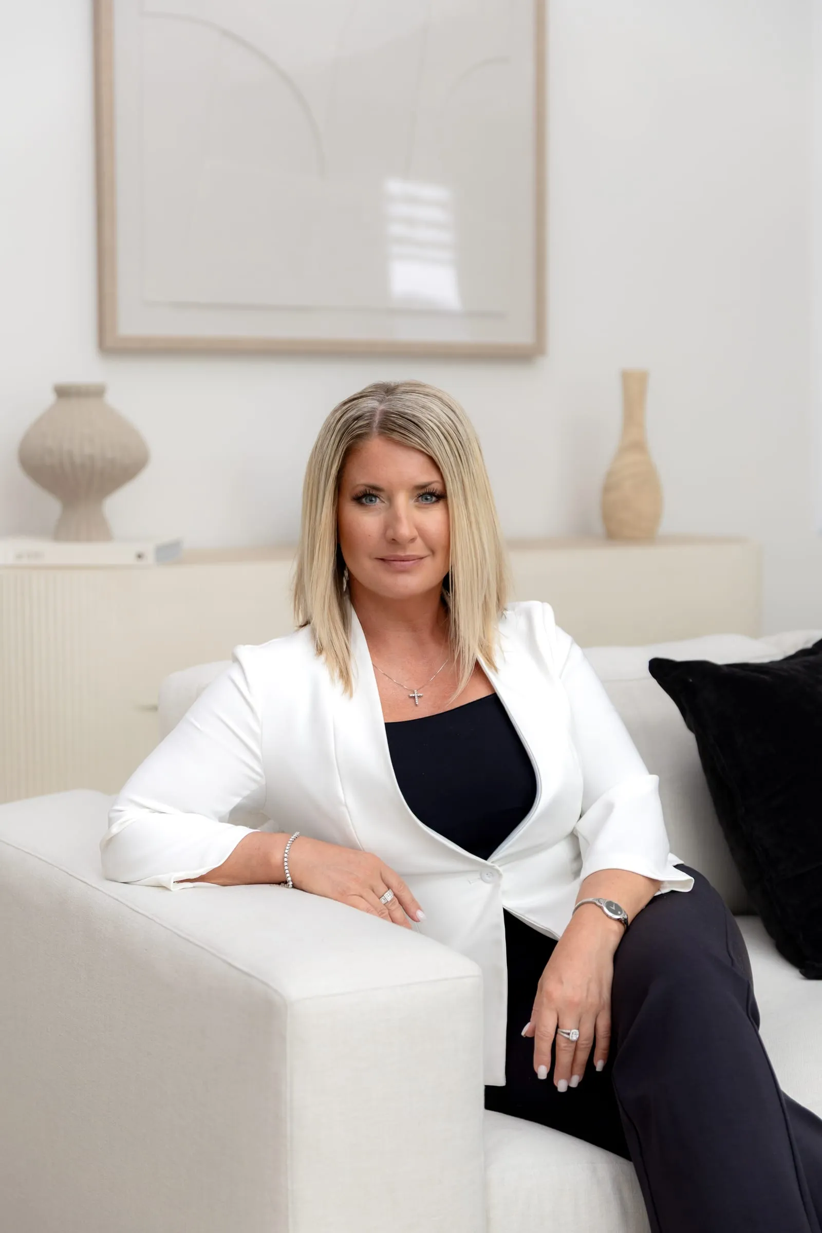 Business owner in a white blazer seated in a bright, modern living room
